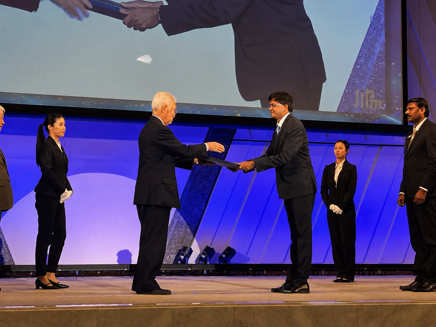 Certificate handover on stage with interpreter and dignitaries present