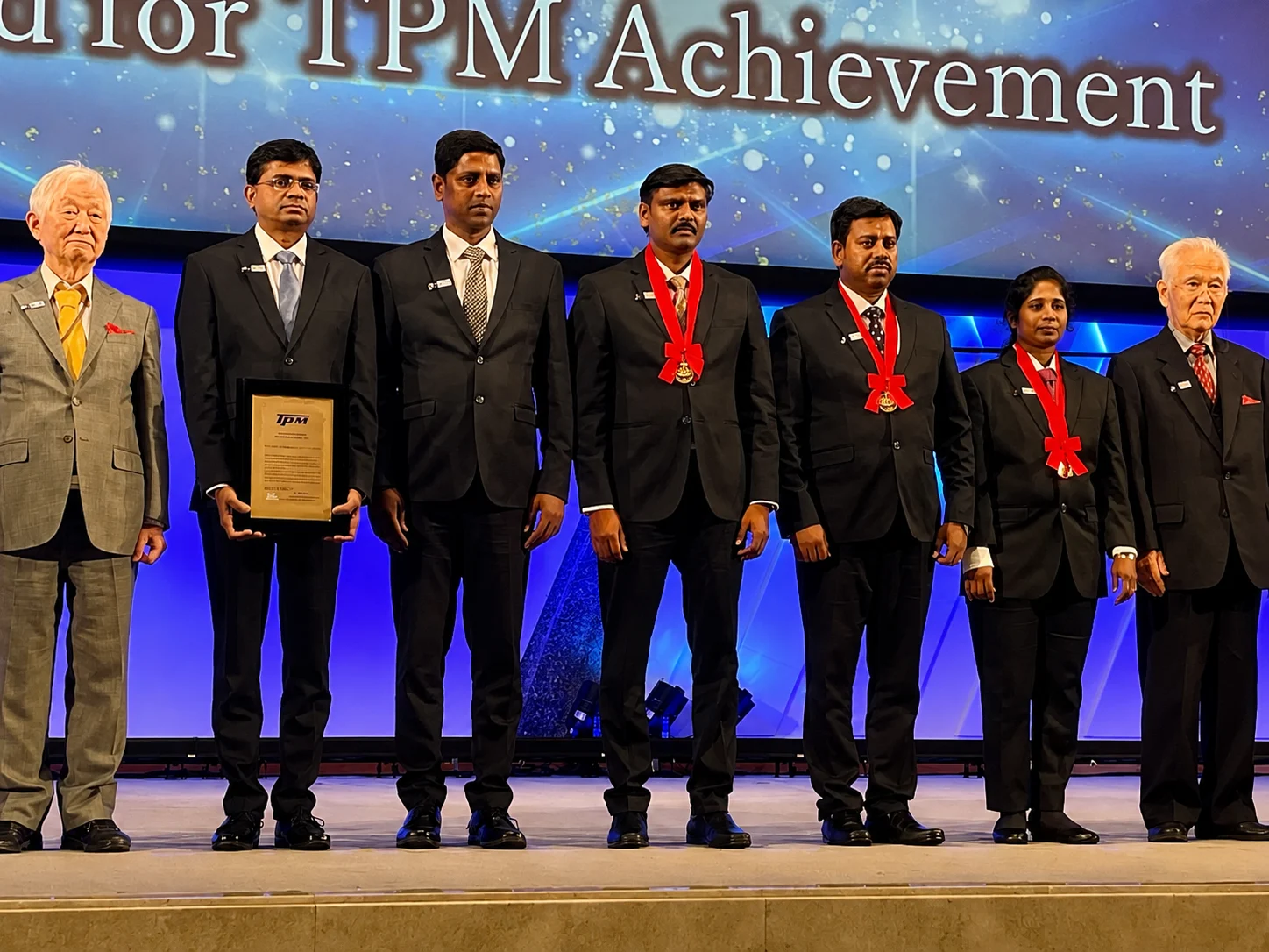 Seven delegates on stage receiving the TPM Achievement award